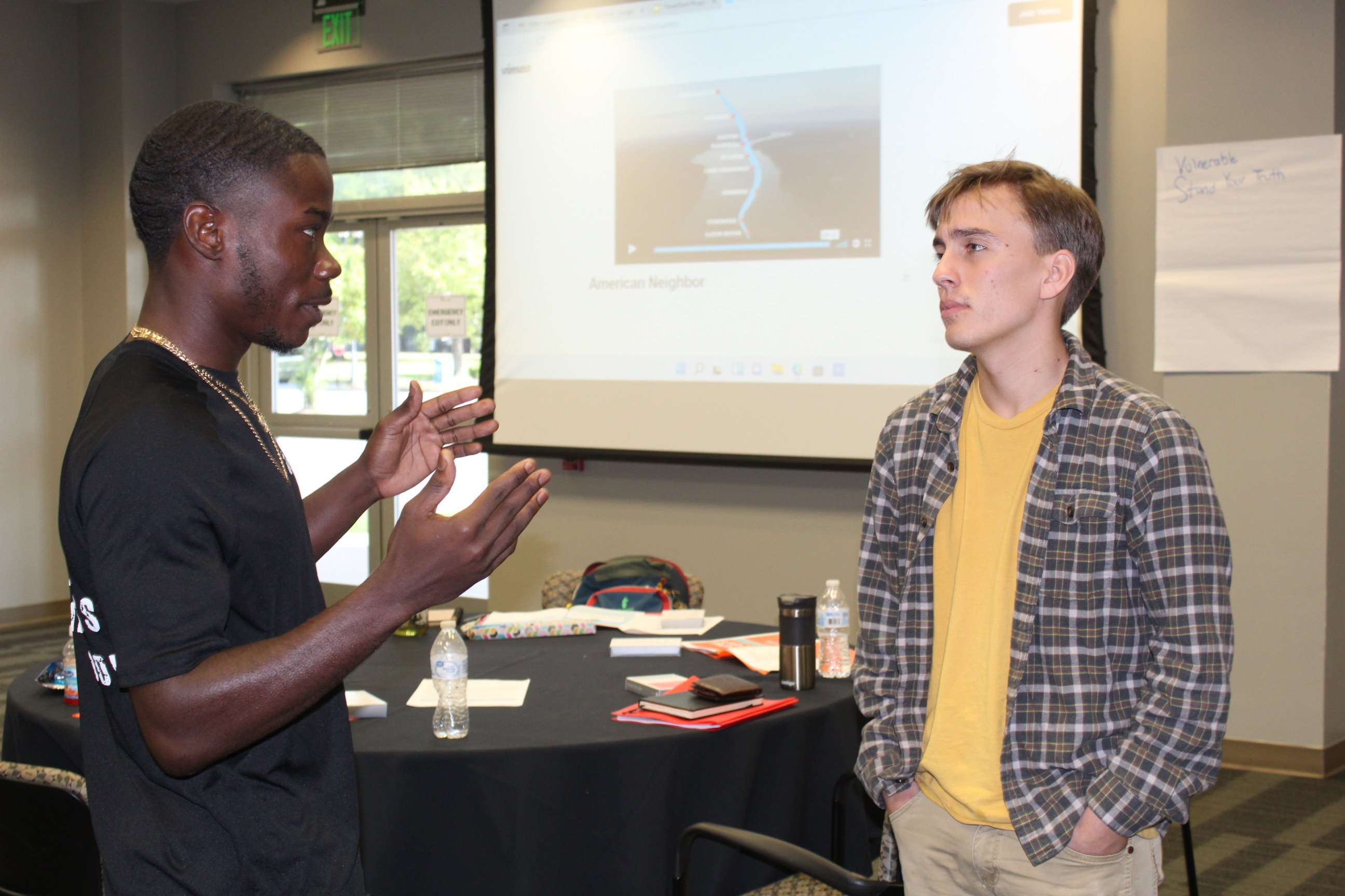 One student gesticulates while talking to another. 